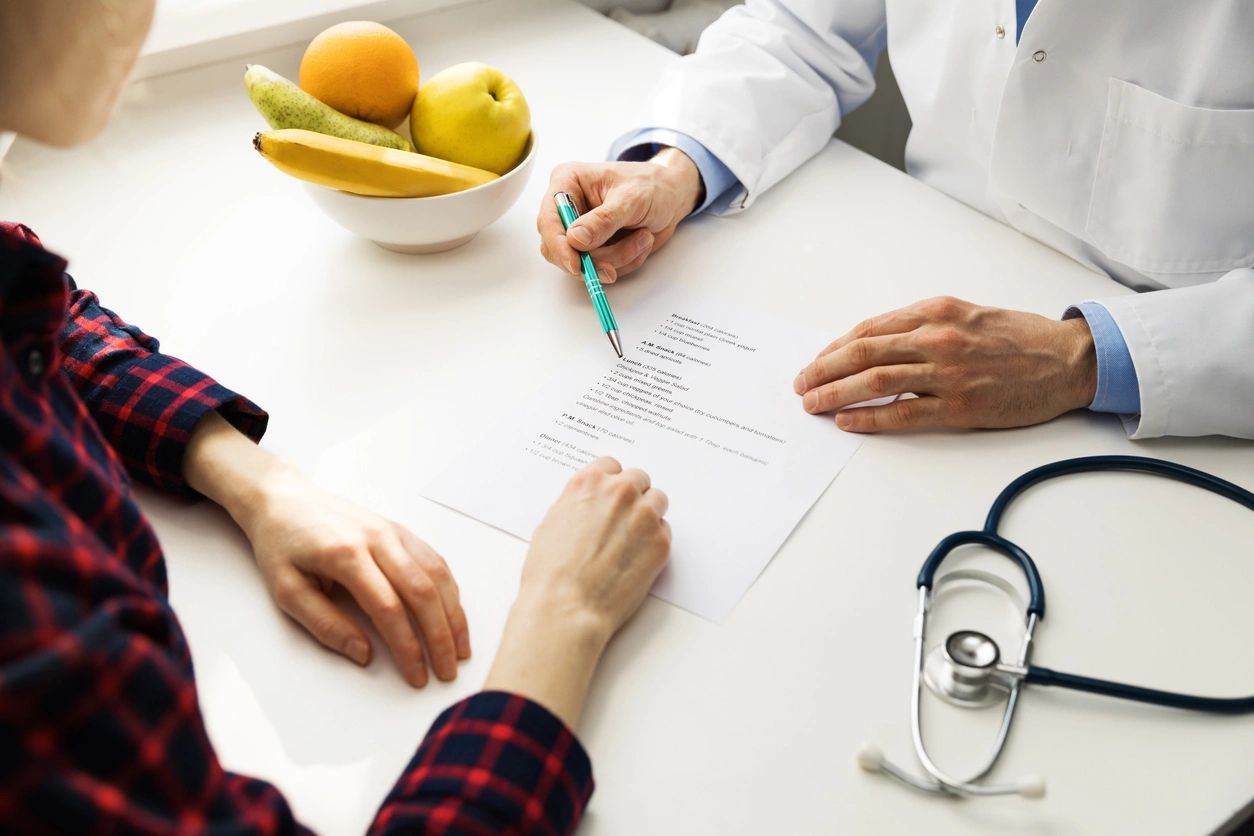 A doctor and patient sitting at a table with fruit.