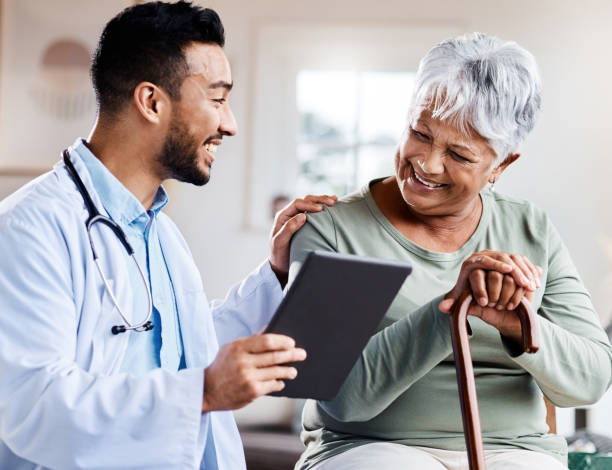 Doctor discussing with elderly woman using tablet.